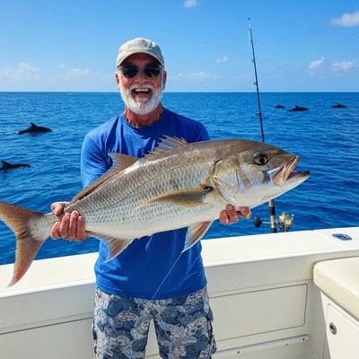 Angler proudly holding a fish caught during a charter, with a beautiful ocean background